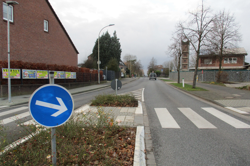 Blick in die Overhetfelder Straße im Niederkrüchtener Ortsteil Elmpt. Im Vordergrund eine Verkehrsinsel sowie dahinter ein Zebrastreifen