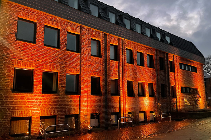 Das im Rahmen der Aktion "Orange the World" mit orangen Strahlern illuminierte Rathaus der Gemeinde Niederkrüchten in Elmpt.