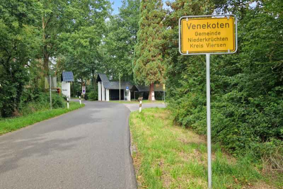 Ortseingangsschild des Ortsteils Venekoten, rechts der Straße. 