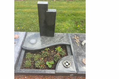 Ein Grab mit Grabstein, auf dem der Fuss einer nicht mehr vorhandenen Lampe montiert ist.