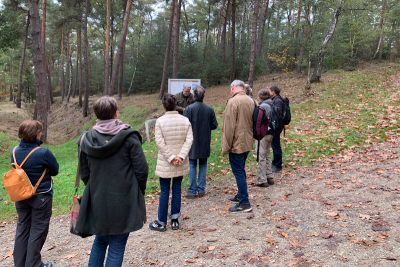 Teilnehmende der Wanderung "Grenzgeschichte(n)" vor einer Hinweistafel am Rande eines Wanderwegs